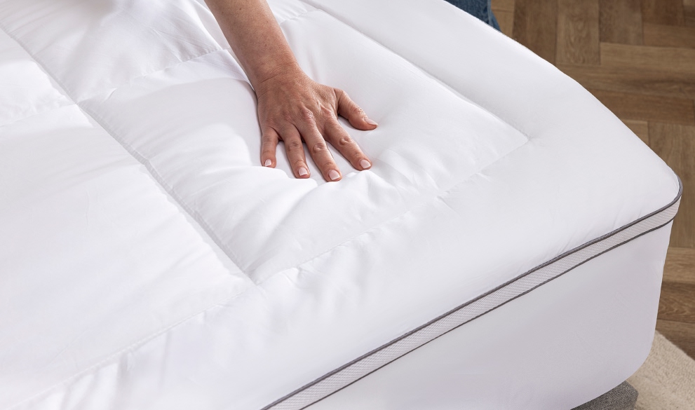 Main sur un surmatelas moelleux pour matelas trop dur